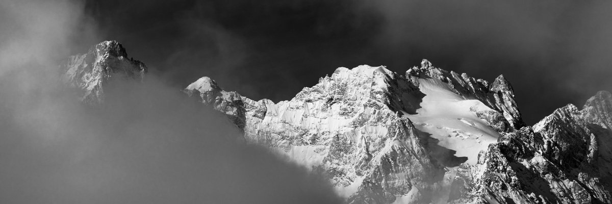 Panoramique d'une montagne derrière les nuages en noir et blanc