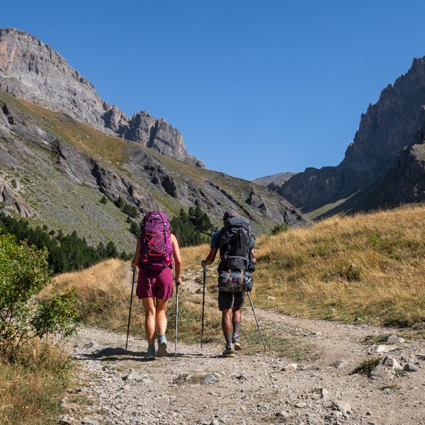 Deux personnes de dos en train de marcher sur un sentier alpin