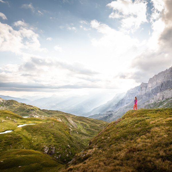 Femme seule au bord d'une falaise admirant le paysage alpin